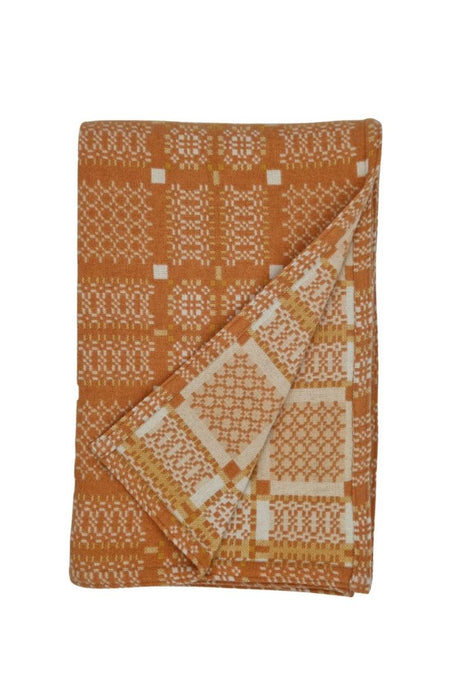 Melin Tregwynt Wool throw with an orange and white woven Knot Garden pattern