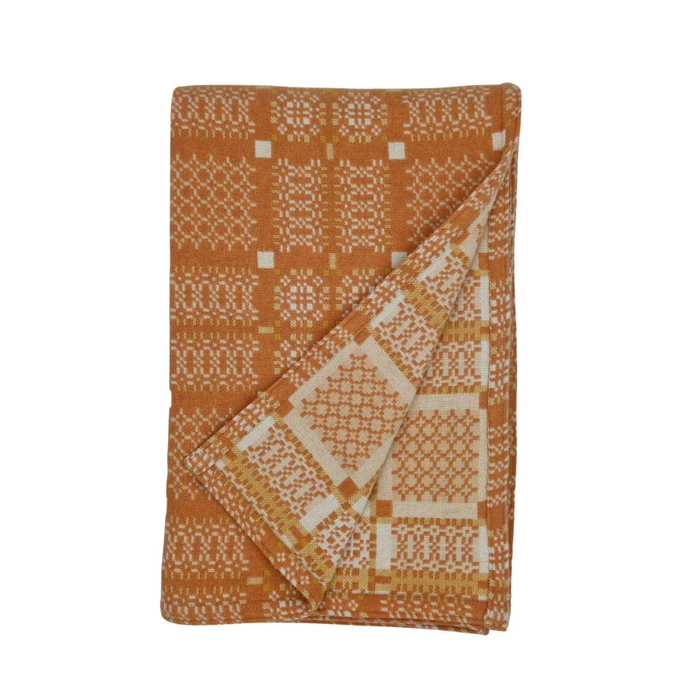 Melin Tregwynt Wool throw with an orange and white woven Knot Garden pattern
