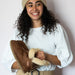 Women smiling while Holding Pair of Bella cognac with a leopard print sheepskins Slippers from shepherd